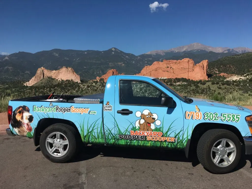 Light-blue Backyard Pooper Scooper service truck with Garden of the Gods in the background